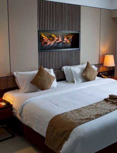 A hotel room with a large bed, two bedside tables with lamps, and a wall decoration. There is also a window with curtains on the right.