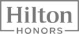 This image is the logo for Hilton Honors, with "Hilton" in a large font inside a rectangular border and "HONORS" in a smaller font below.
