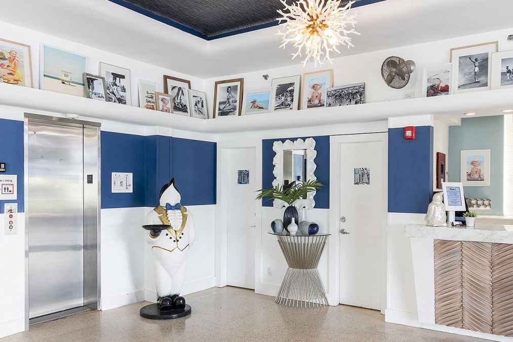 A lobby with an elevator, reception desk, a penguin statue, and a mirror