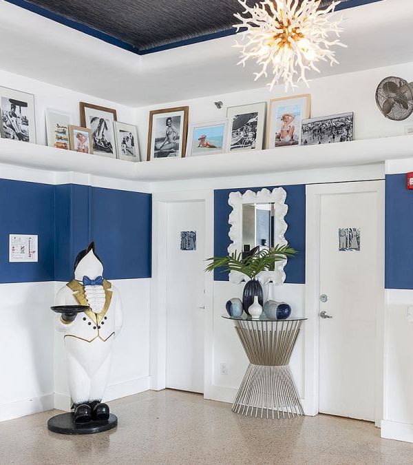 A lobby with a statue, artwork, plant, and chandelier