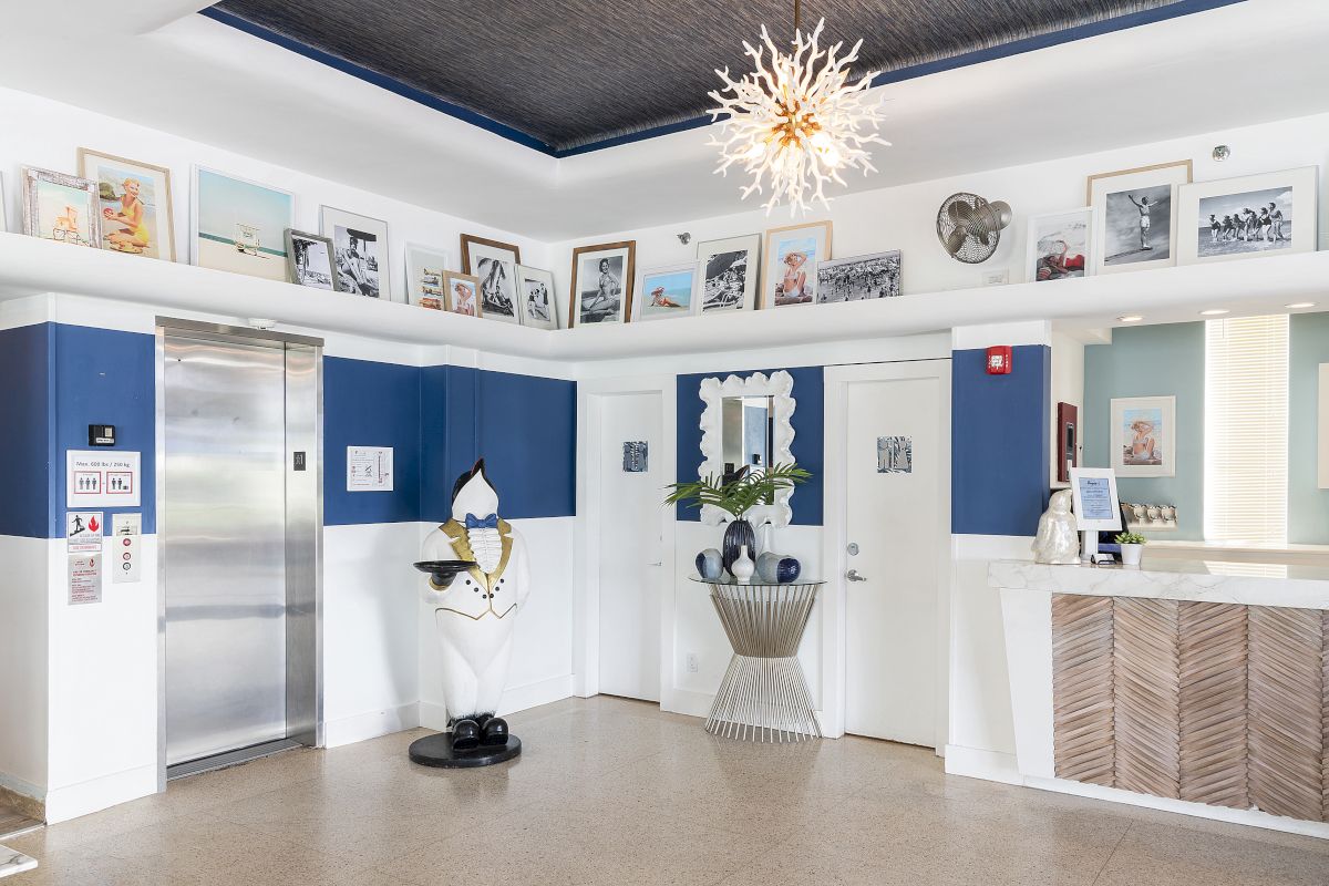 A hotel lobby with a modern design, featuring a statue, artwork, and a reception desk.