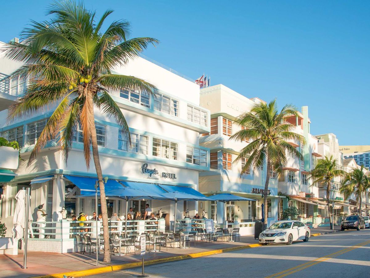 A white building with blue trim and palm trees in front of it.