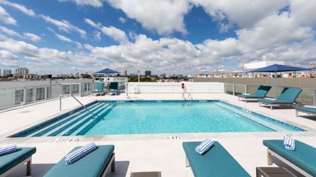 A rooftop pool with lounge chairs and city view